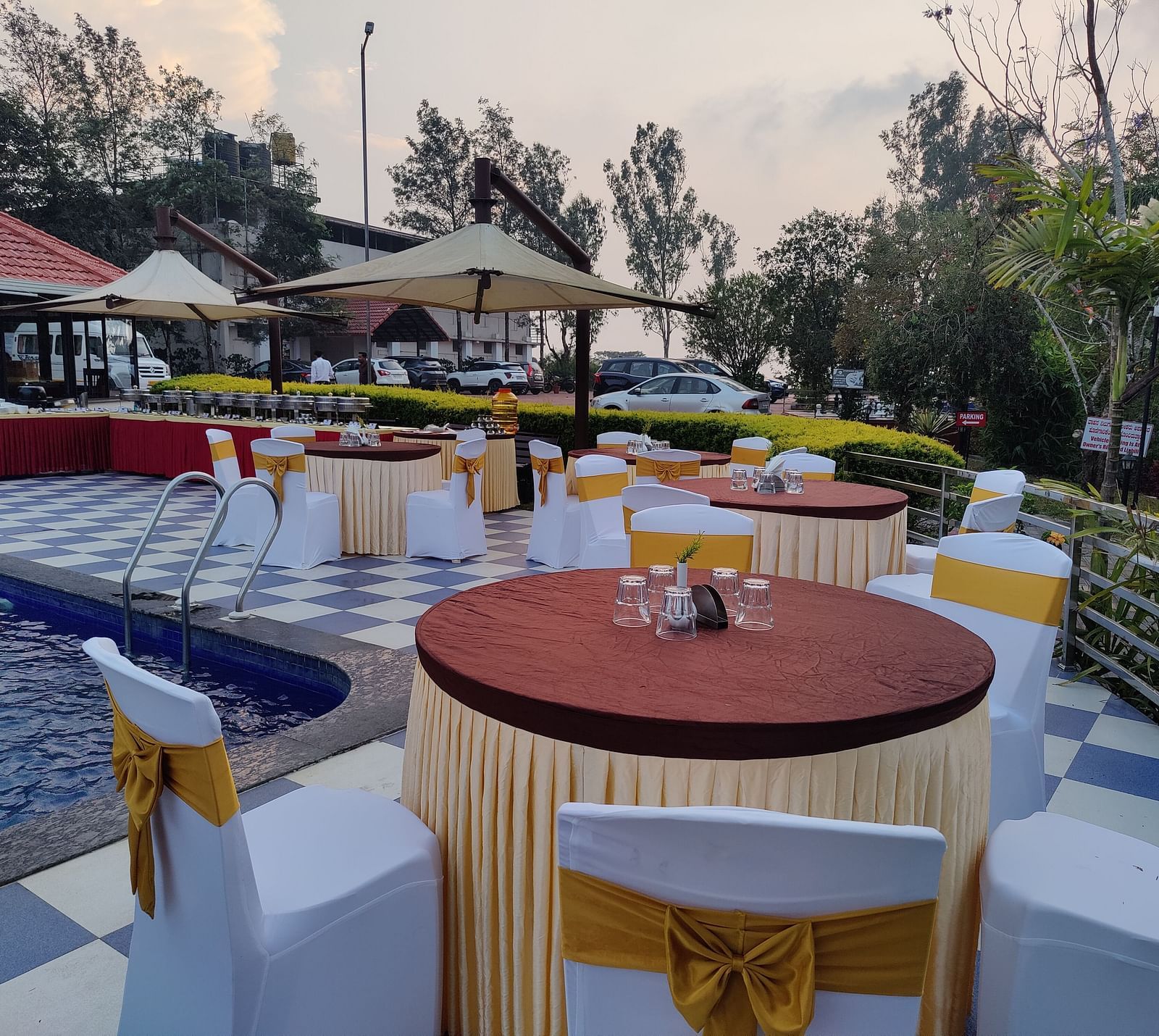 Outdoor dining area with round tables and umbrellas | Open Deck | Woodstock Resorts, Coorg