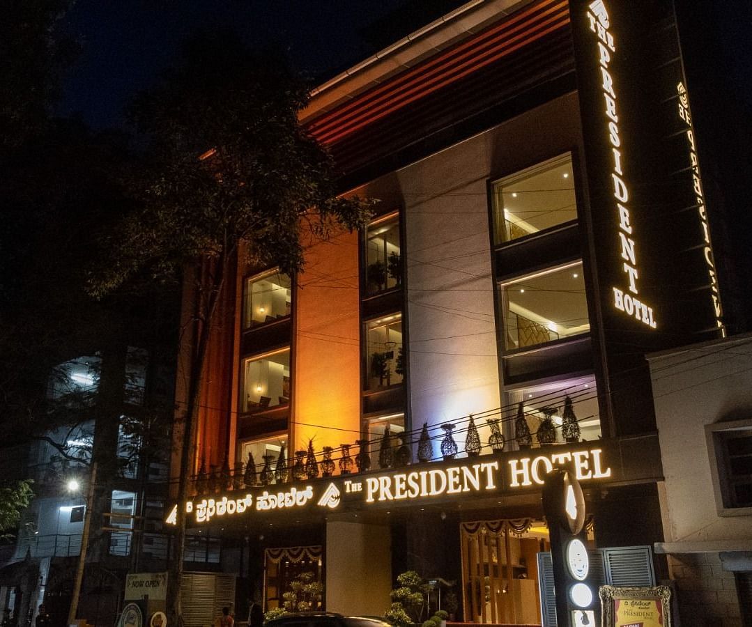 An image of night view of a hotel facade with warm lighting - The President Hotel, Kumara Park, Bangalore