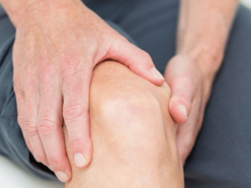 A person holding their knee with both hands while being seated