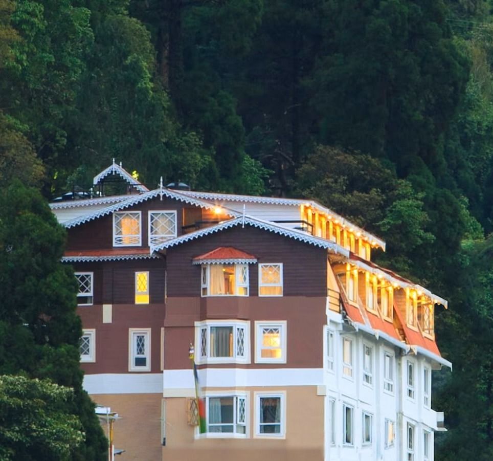 Front facade view of Summit Hermon Hotel & Spa, Darjeeling, surrounded by lush greenery
