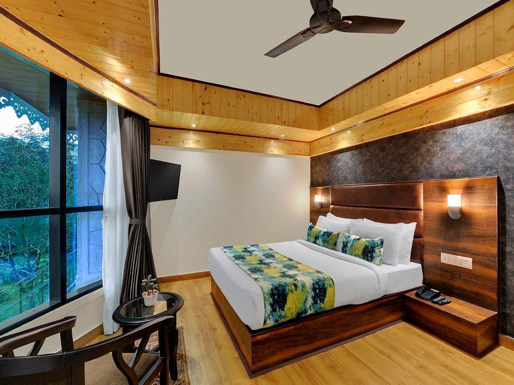 An image of Sumitel Queensyard premium room with king size bed, ceiling fan and an expansive window