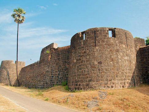 an far out view of Madh Fort with a small road on the side and blue sky in the background