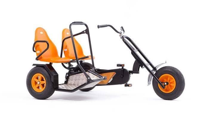 Side view of a two-seater orange pedal go-kart with black frame.