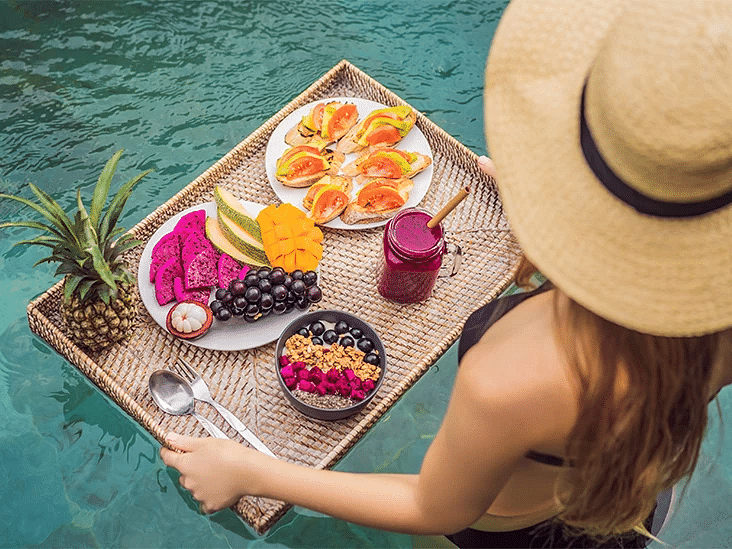 A woman in a sun hat relaxing by the poolside with a platter of fresh fruit - S Hotel Montego Bay, Jamaica