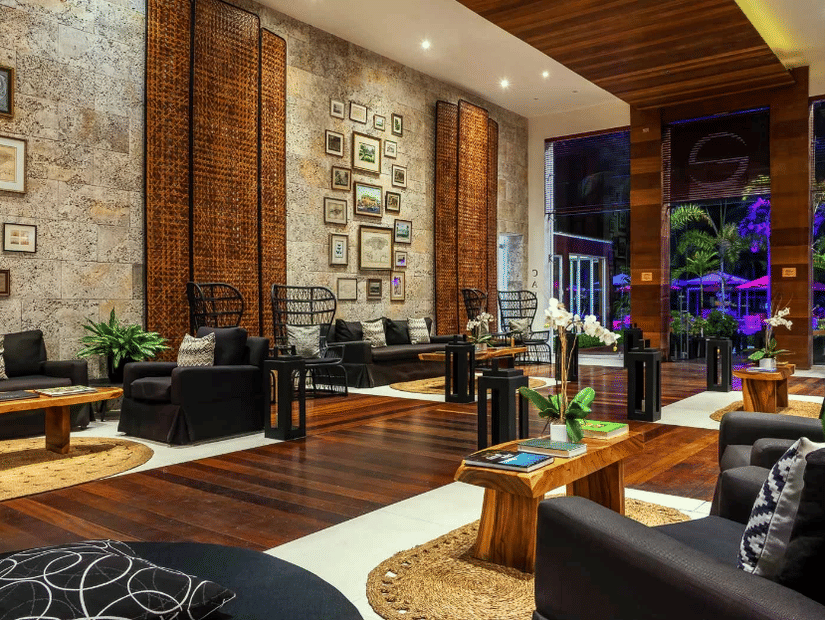 A warmly lit hotel lobby in Jamaica with teapoys and couchec at S Hotel Montego Bay, Jamaica