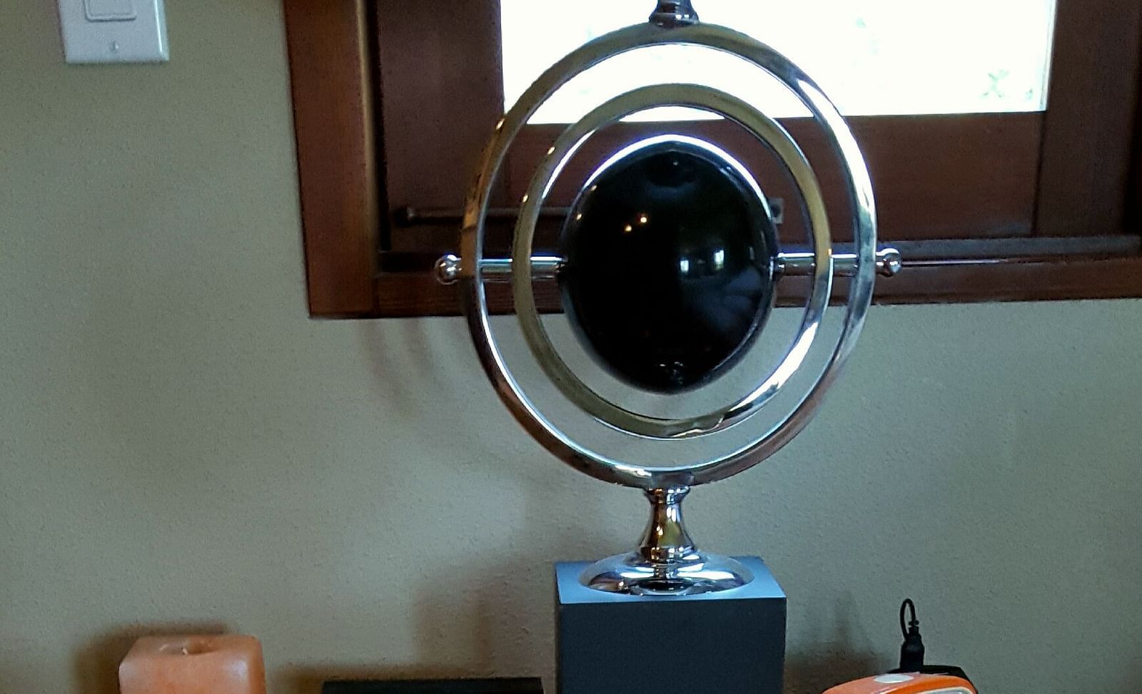 A stylish wooden desk featuring an alarm clock, a scented candle, and a perpetual motion desk toy - Brewery Gulch Inn & Spa