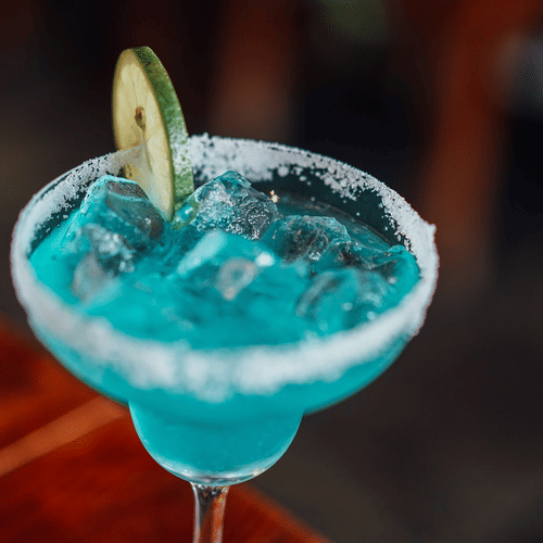 A blue coloured drink on ice, with a wedge of lime
