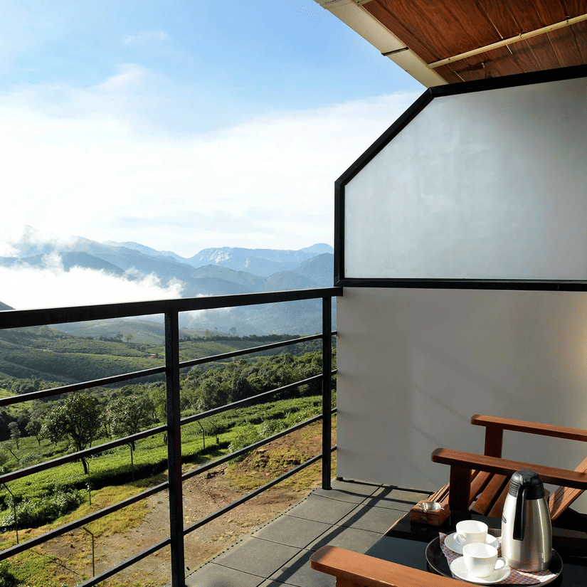 Shot of the mountains from the balcony of the villa that has two wooden chairs | Ibex Stays and Trails, Valparai (Tale Rock)