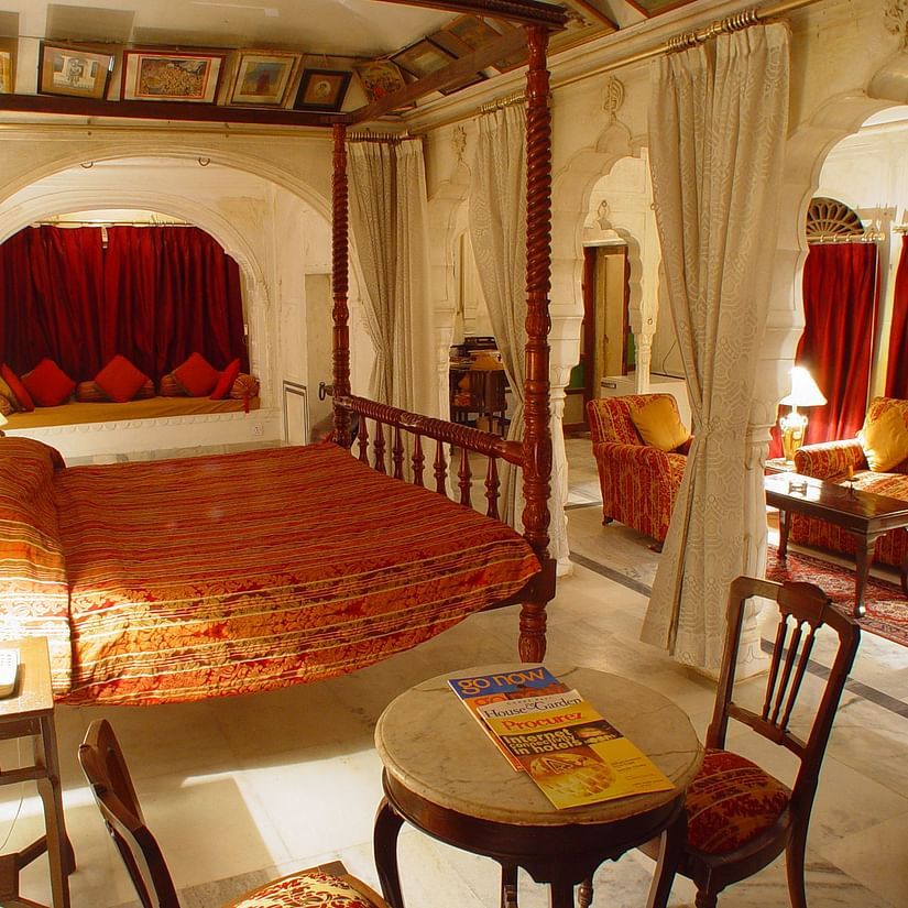 a bedroom with a large bed and chairs to sit  - Hotel Castle Mandawa, Jhunjunu