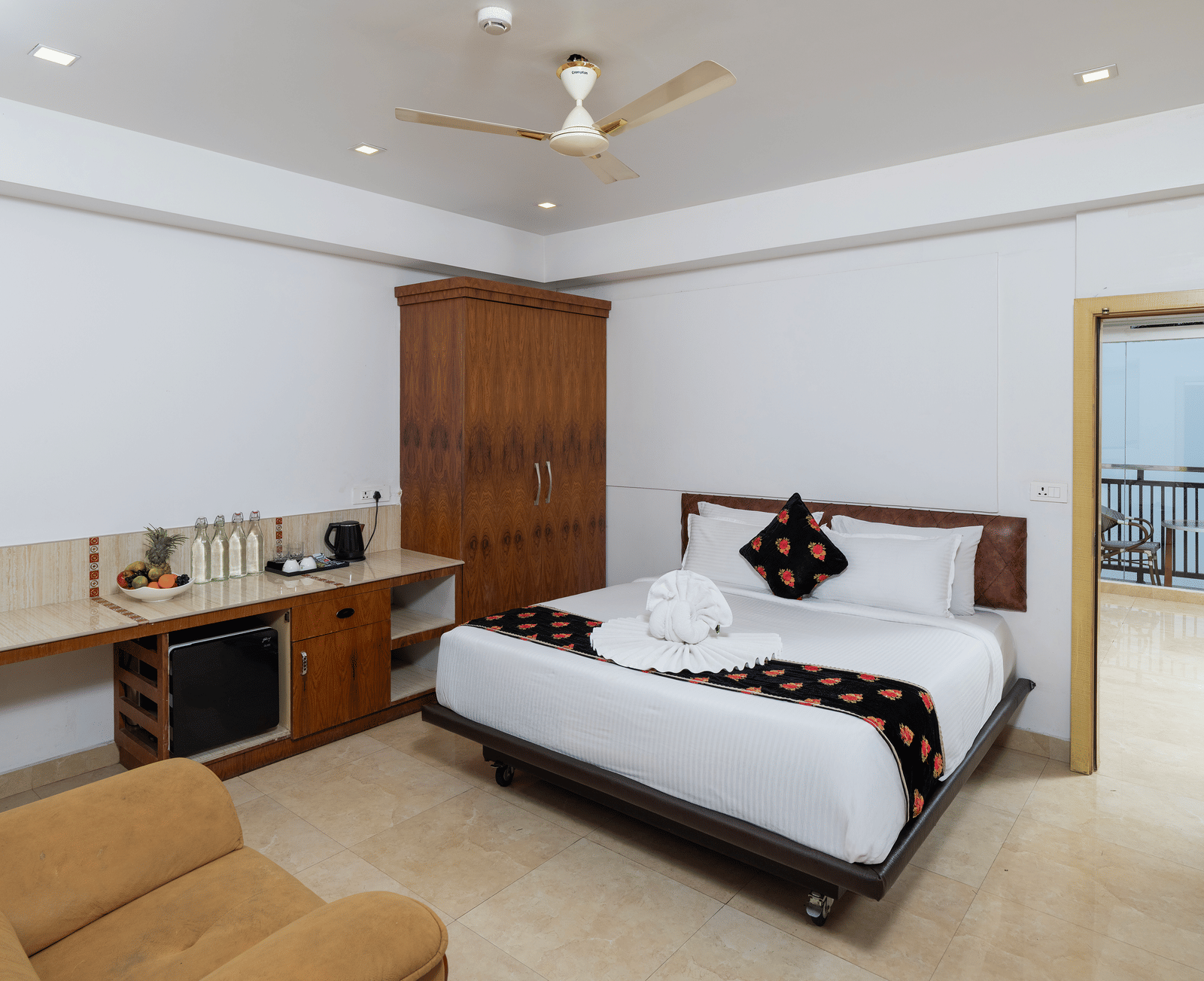 A bedroom in Family Interconnected Club Suite at Parakkat Nature Hotel and Resorts, Munnar with a double bed, a ceiling fan, a single-seating sofa, and an opening to another room.