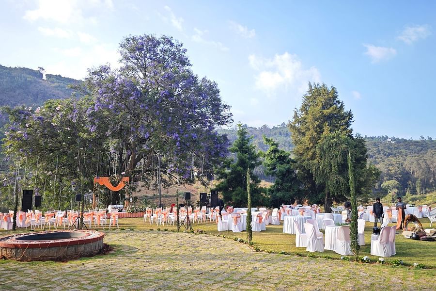  Scenic view of an outdoor wedding venue during the day with guests, chairs, and an altar under a blooming purple-flowered tree in Coonoor - Ibex Stays & Trails, Coonoor (Leewood).