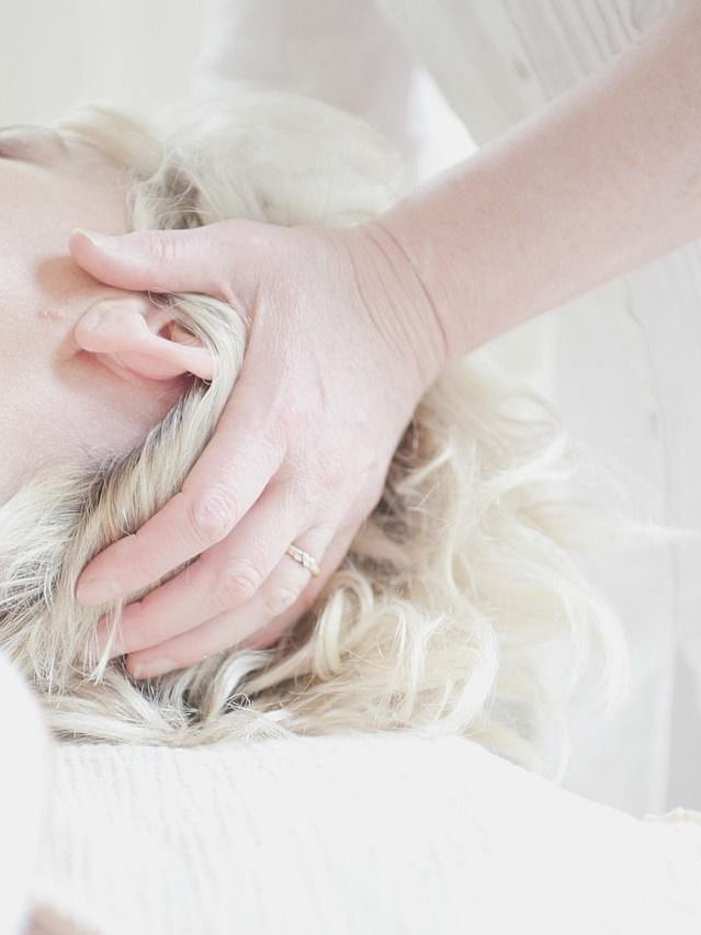 Gentle hands give a relaxing head massage to someone with light coloured hair.