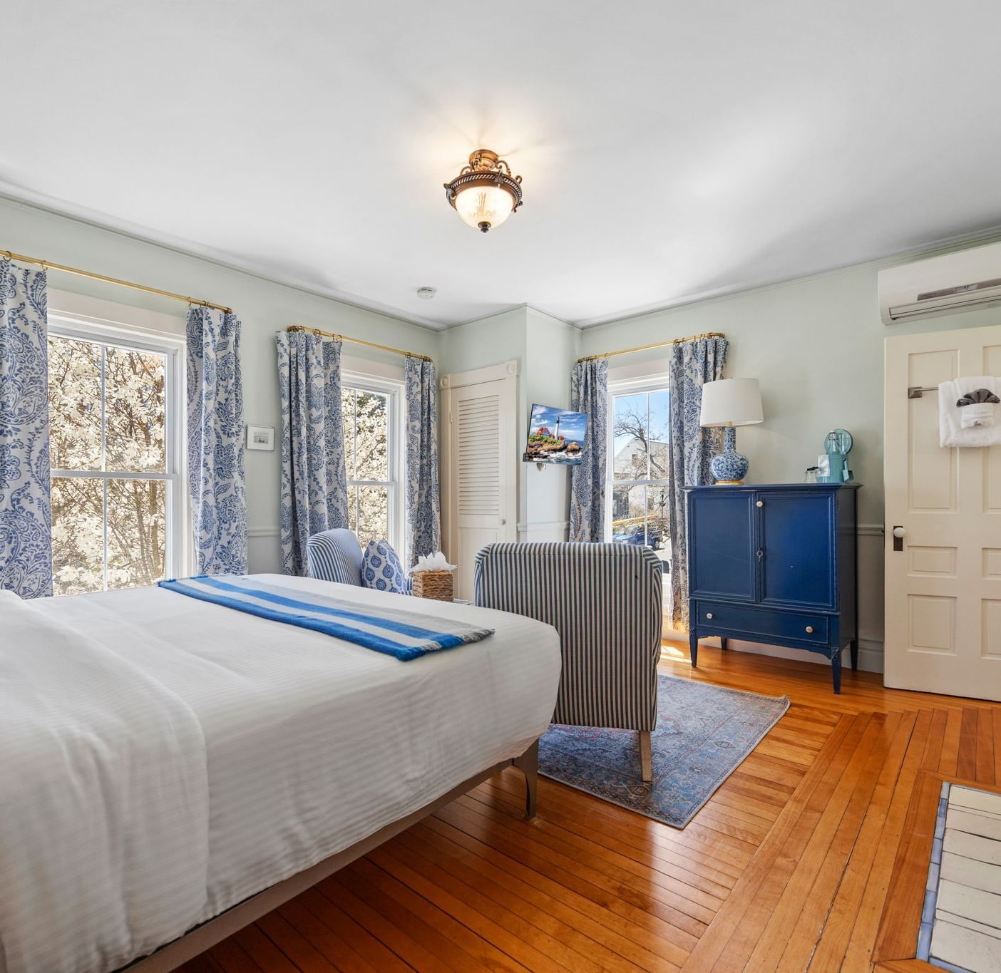 A air conditioned room with queen size bed and floral curtains at Hartstone Inn