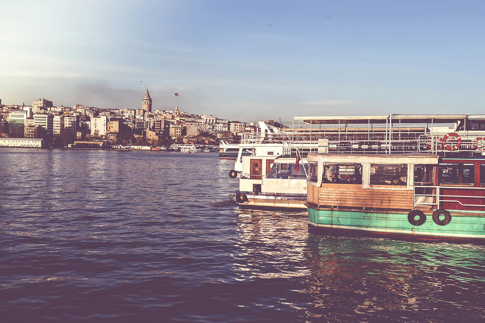 Two ferries side by side on a waterbody with buildings on the land in the background