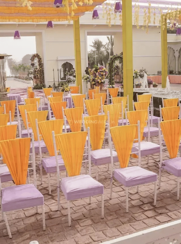 Rows of chairs with yellow coverings arranged in a courtyard with columns at Beelwa Palace, Jaipur.