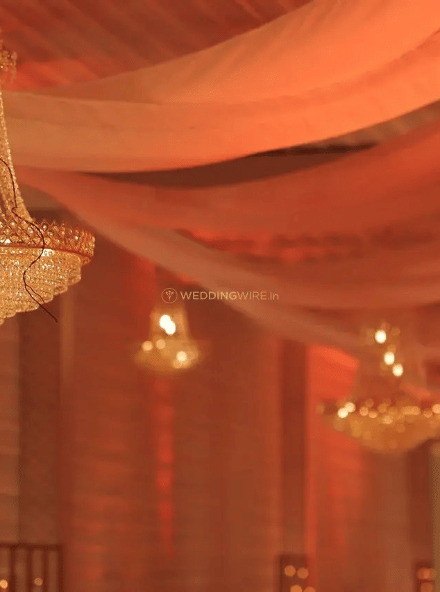 Ceiling with chandeliers and pink drapes hanging over a hall at Beelwa Palace, Jaipur.