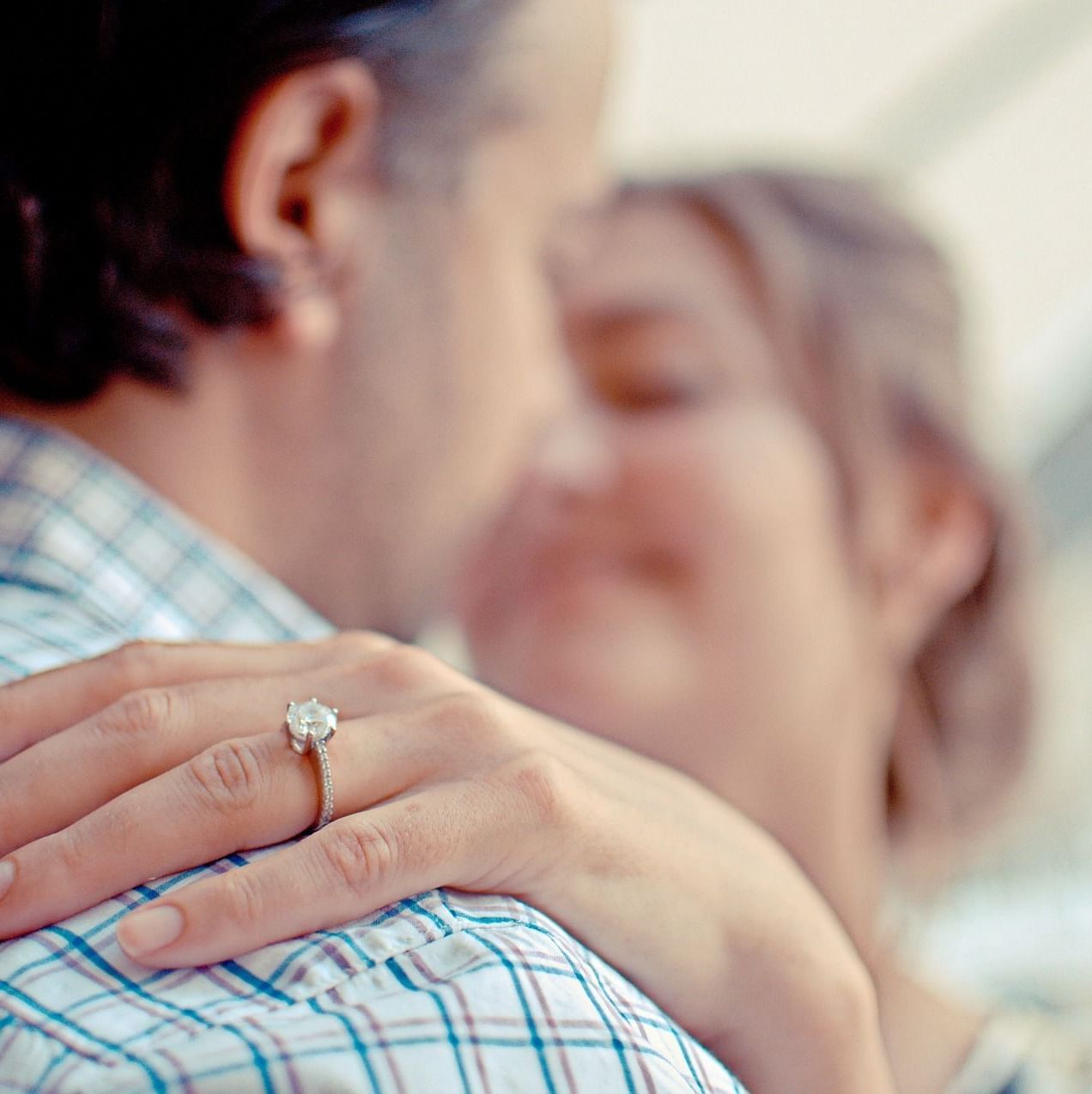 image of a happy couple hugging each other with more focus on the ring on the hand of the woman