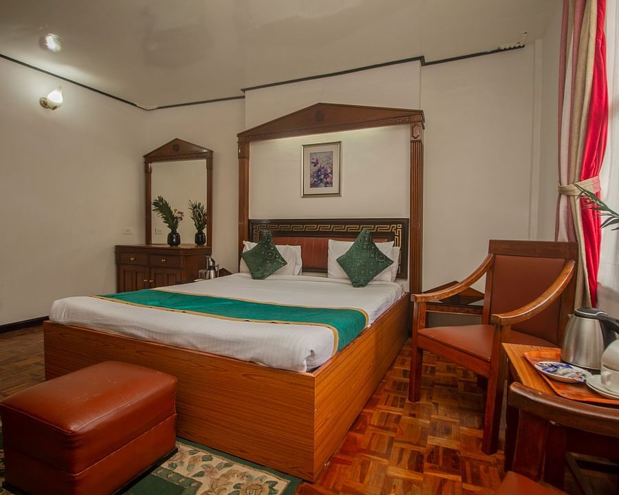 An image of a Club Room featuring a double size bed, dressing table, chair and a table with tea and coffee maker at Central Hill Resort, Gangtok