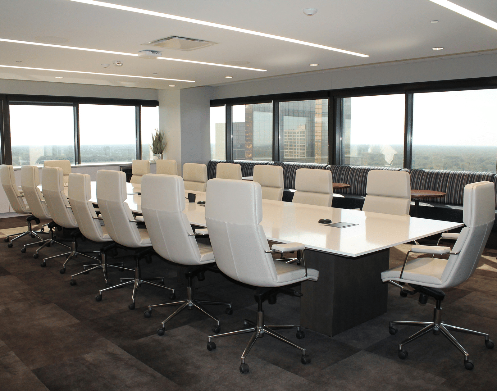 A long white rectangular table surrounded by white chairs in a room with windows overlooking a horizon | Hotel Galadari