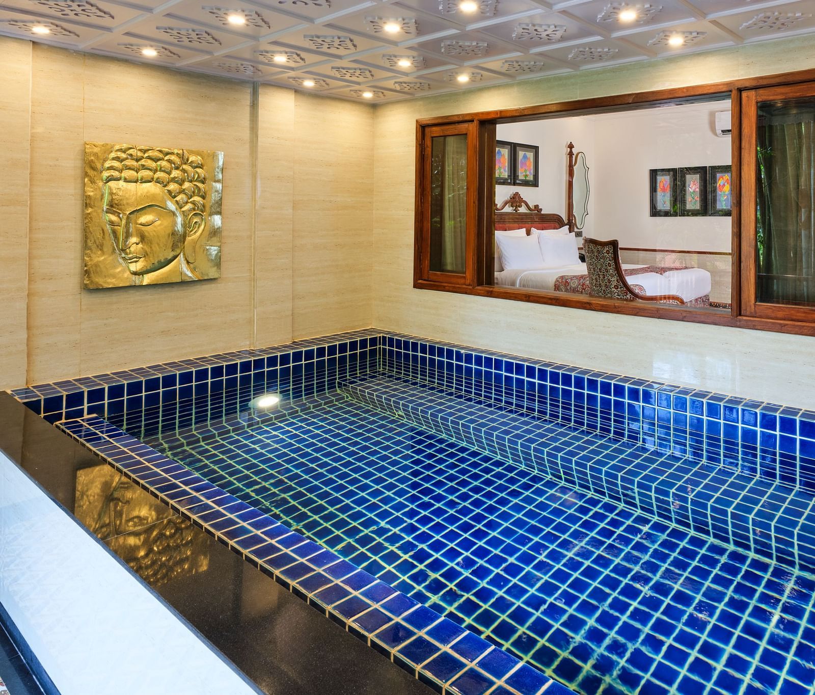 Royal Villa private swimming pool with a gold artwork on the wall. a window through which the bedroom can be seen.