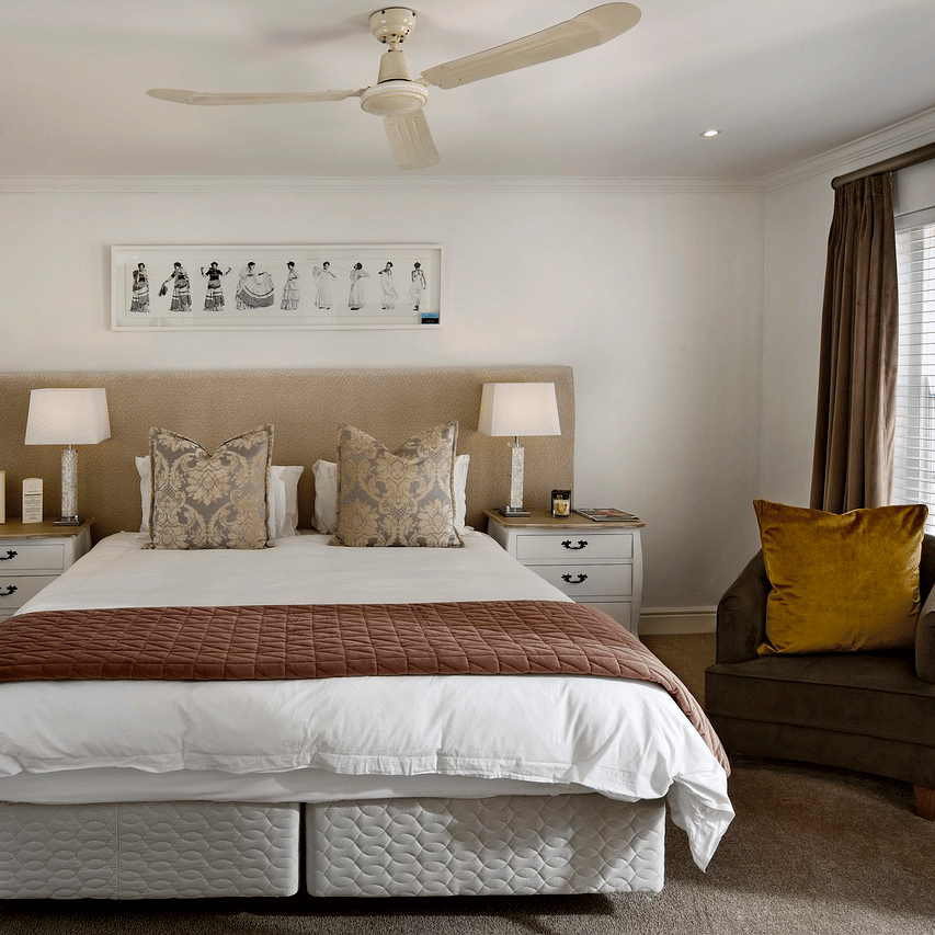 A double bed with a ceiling fan hanging over it in a bedroom.