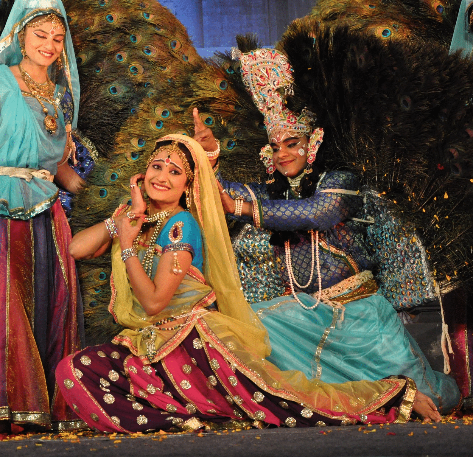 An image of drama stage with three people in traditional attire performing an act 