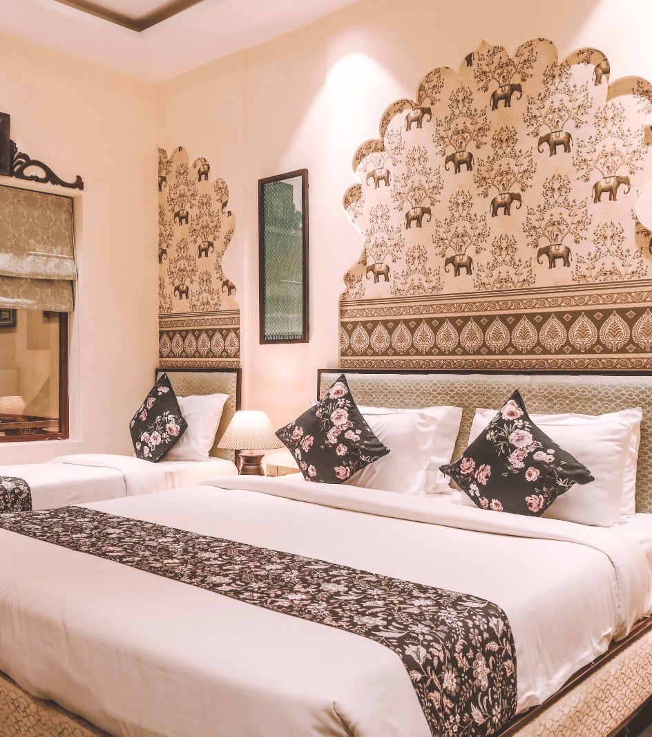 Bedroom with double bed, lamps, patterned wall design and mirror at Beelwa Palace, Jaipur