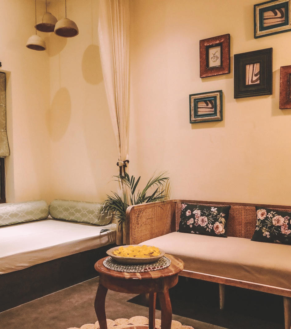 Small seating area with wooden furniture, window and wall frames at Beelwa Palace, Jaipur