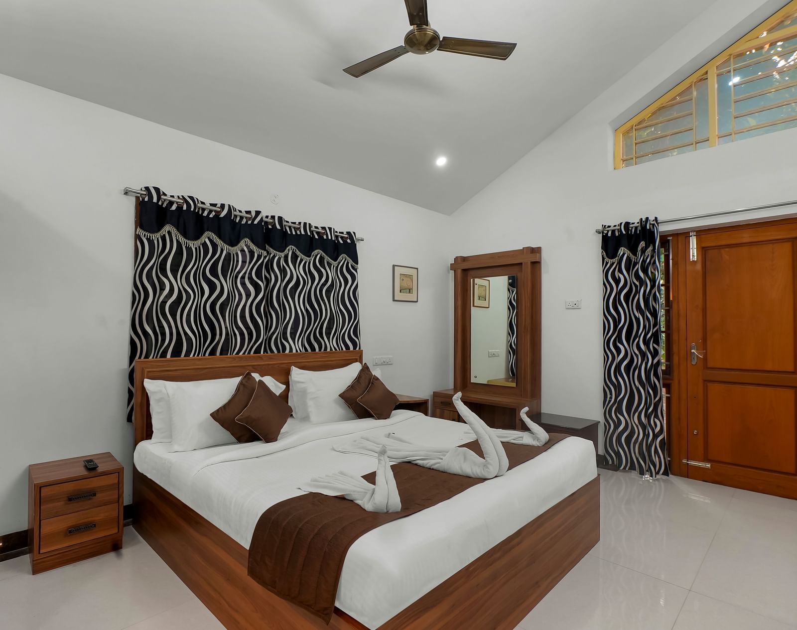 Diagonal view of a room showing a large bed with towel decorations at WOW Bungalow, Yercaud. 