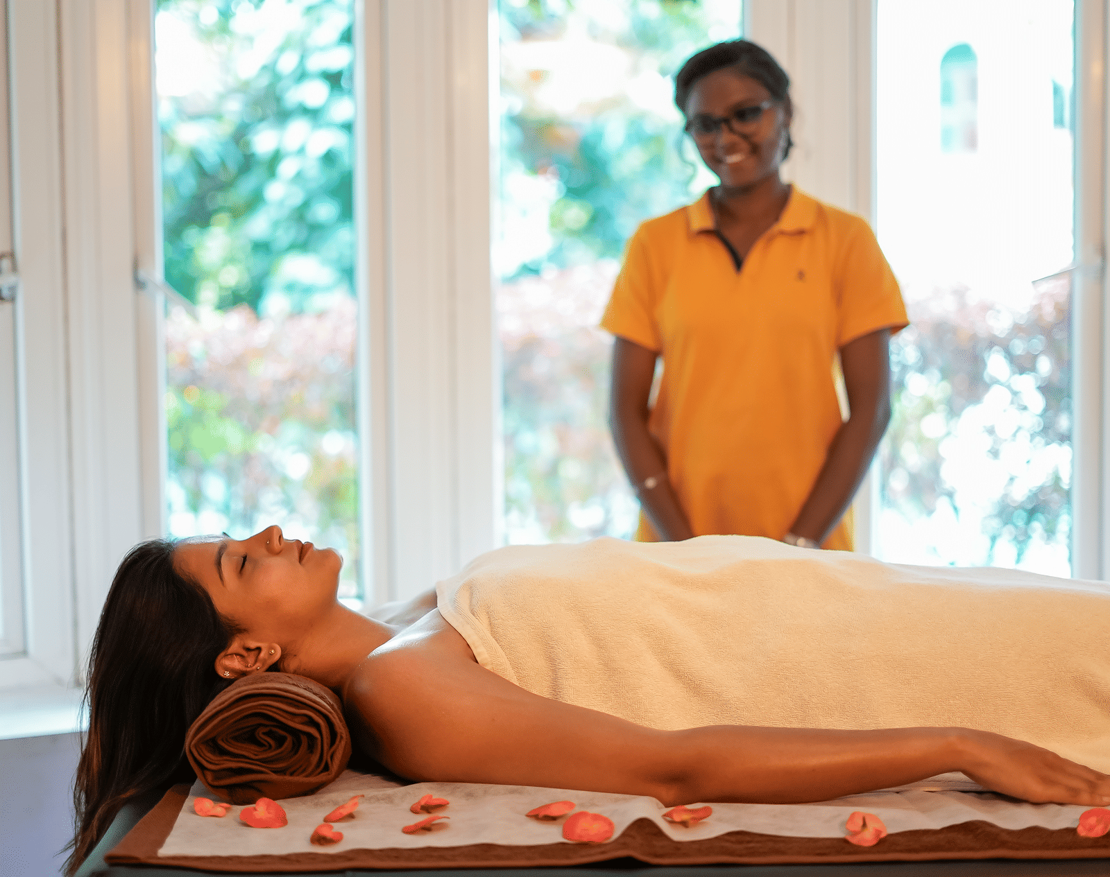 A lady lying on a spa bed and a therapist standing beside her at WOW Bungalow, Yercaud.
