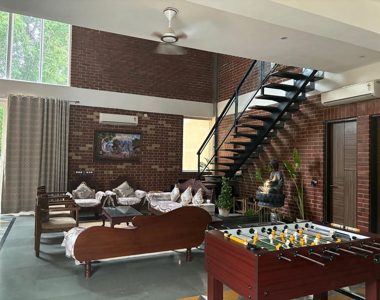 A modern living room with a foosball table, seating area, and a staircase.