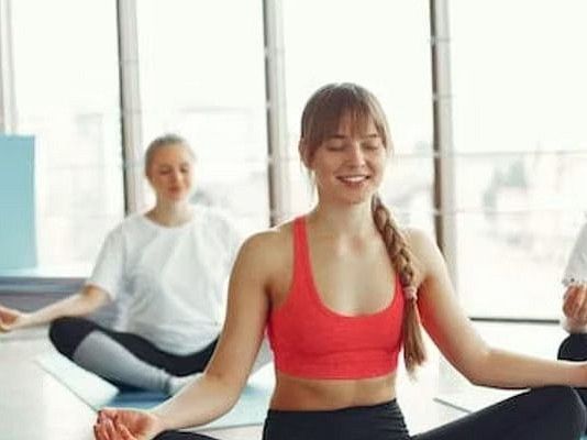 Women performing yoga poses on mats in a serene studio setting.