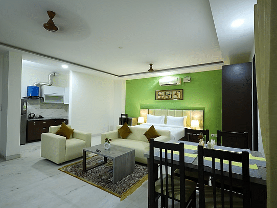 A hotel suite with a green accent wall, living area, dining table and an open kitchenette - Lime Tree Golf View, Golf Course Road
