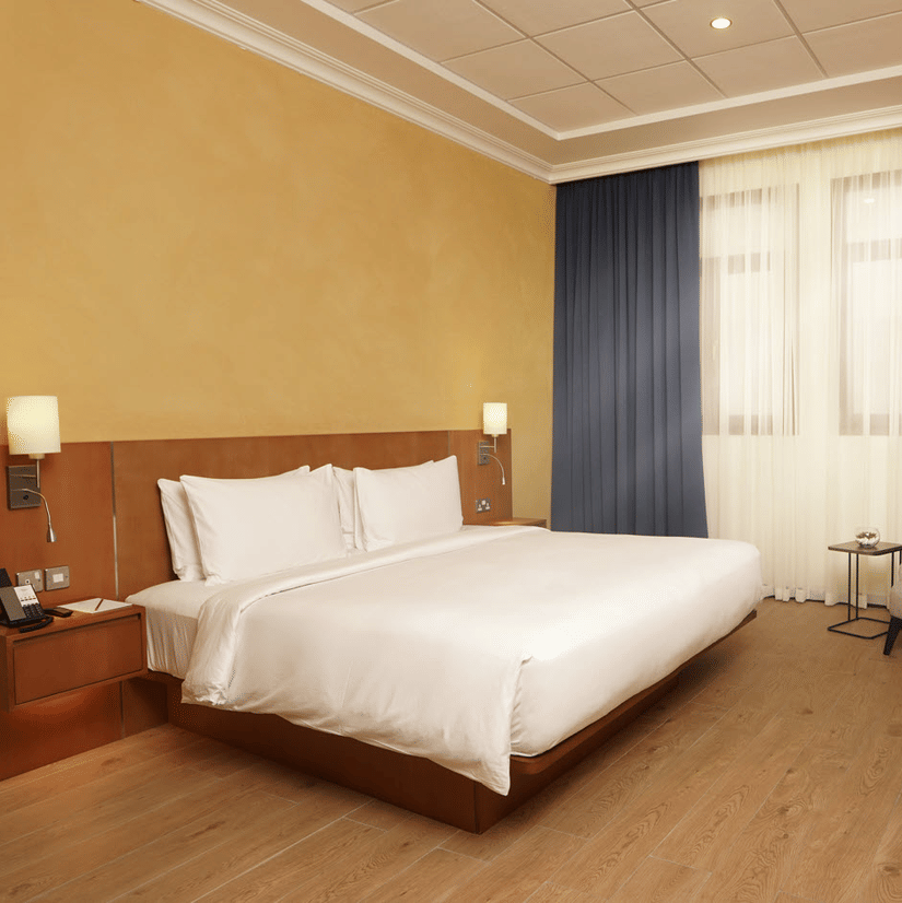 Elegant Classic King Room featuring a plush king size bed, warm interiors, and modern comforts at La Maison Hotel in Doha, Qatar.