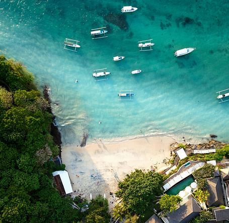 Aerial view of boats anchored near the shore and buildings along the coastline