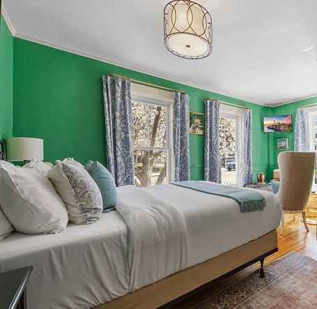 A bedroom with , green walls, and large windows lat Hartstone Inn.