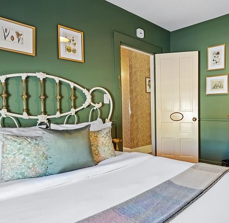 Green-themed bedroom with antique furniture and metal bed frame at Hartstone In