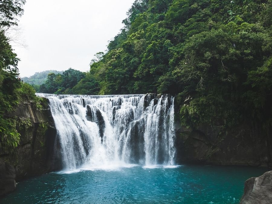a waterfall cascading around lush green forest - Ibex River Resort, Pollachi