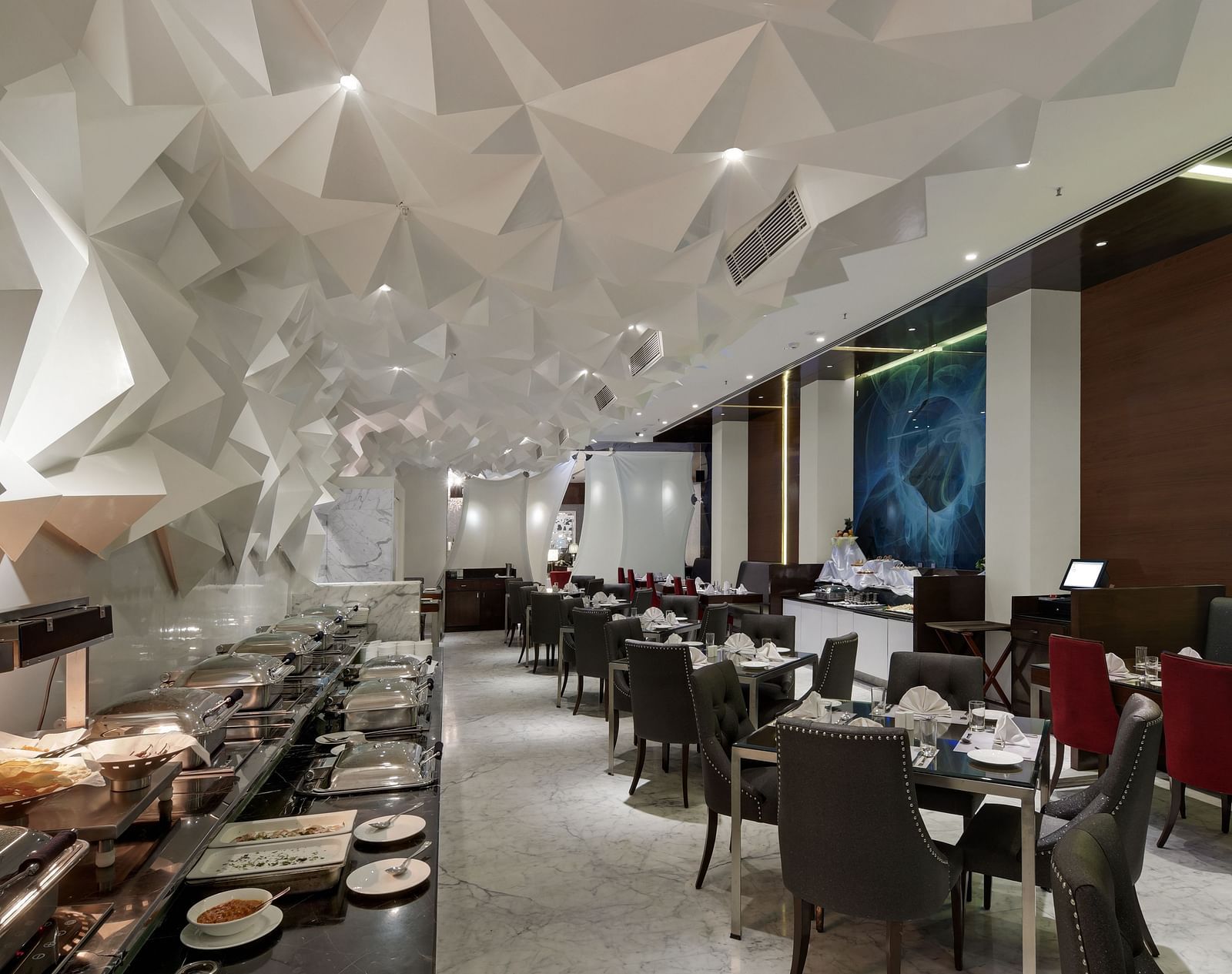 Modern indoor dining area with elegant seating, buffet setup, and artistic geometric ceiling decor