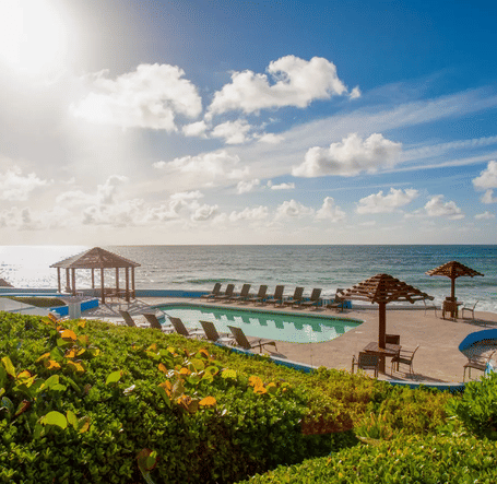 Wooden deck with thatched umbrellas and lounge chairs by the beach | Abaco Inn
