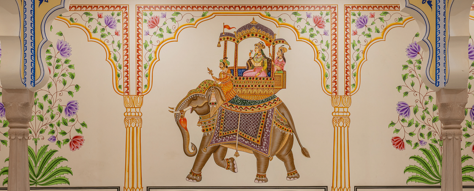 four leather arm chairs placed in front of a beautiful wall with a painting of an elephant carrying a palanquin - Brij Castle, Jaipur