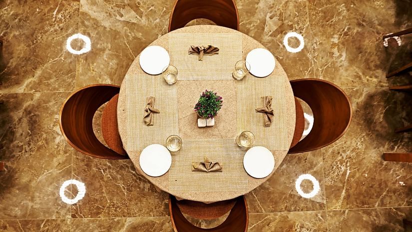 A view of the table from above with four chairs tucked inside the table and cutlery on it - VITS Devbhumi, Dwarka