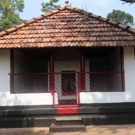 Kaimada shrine with red steps and tiled roof in Kodagu.