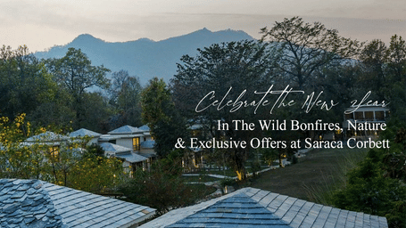 A rooftop view of a resort surrounded by lush green mountains, highlighting a serene and luxurious mountain escape, ideal for a New Year celebration at Saraca Corbett.