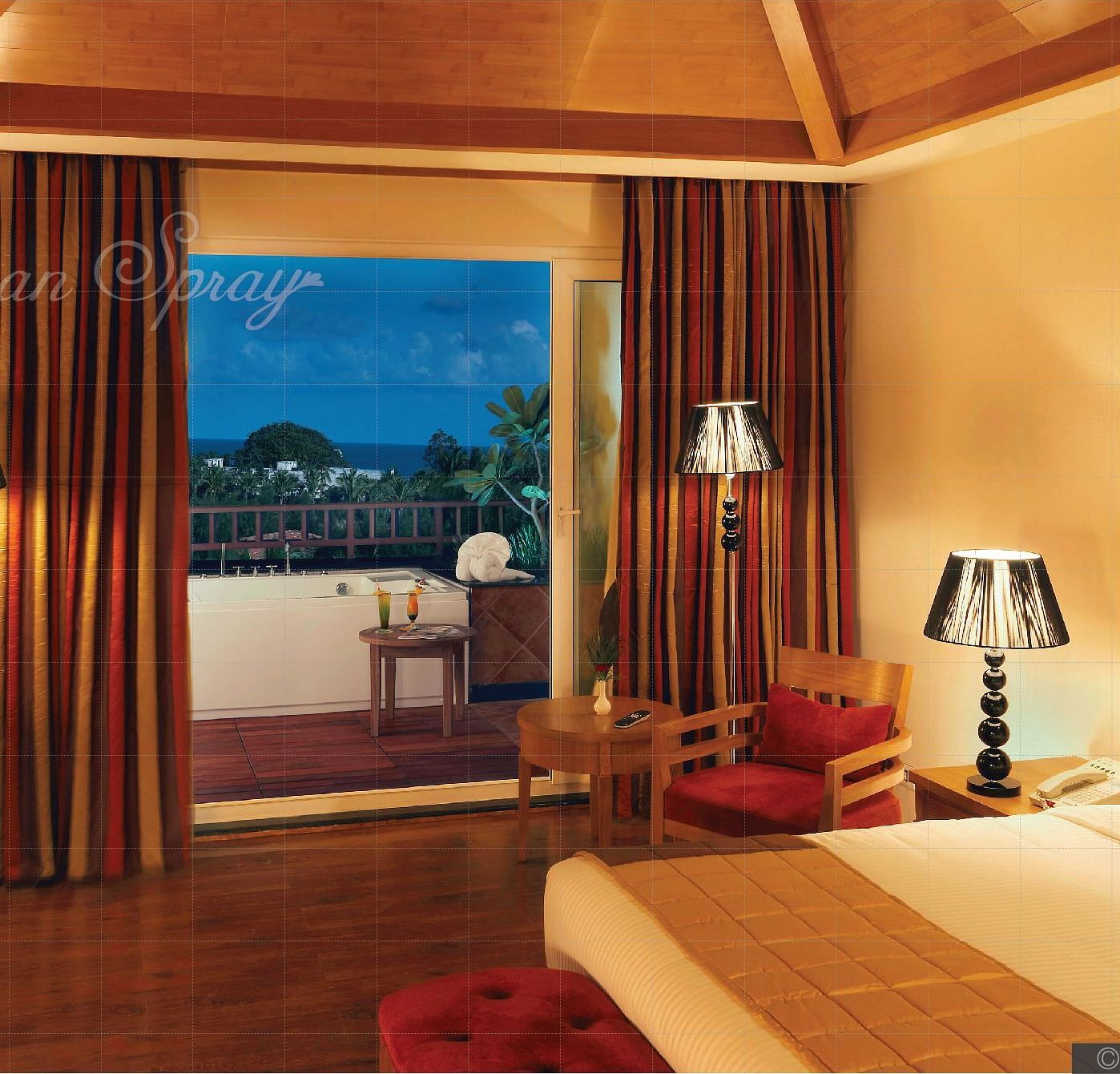 a double bed with side lamps and a tv opposite the bed inside Heavens at Ocean Spray, Puducherry.