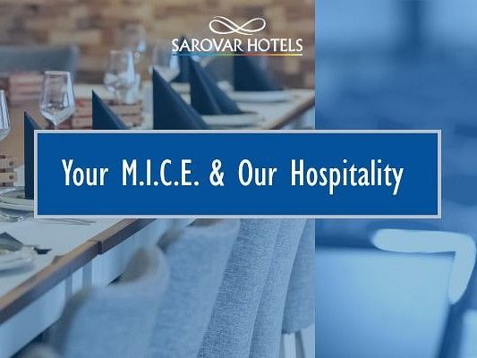 A promotional banner for Sarovar Hotels featuring a split image: on the left, a neatly set dining table with folded napkins and wine glasses, and on the right, a microphone in front of an empty conference hall. The text in the centre reads, 'Your M.I.C.E. 