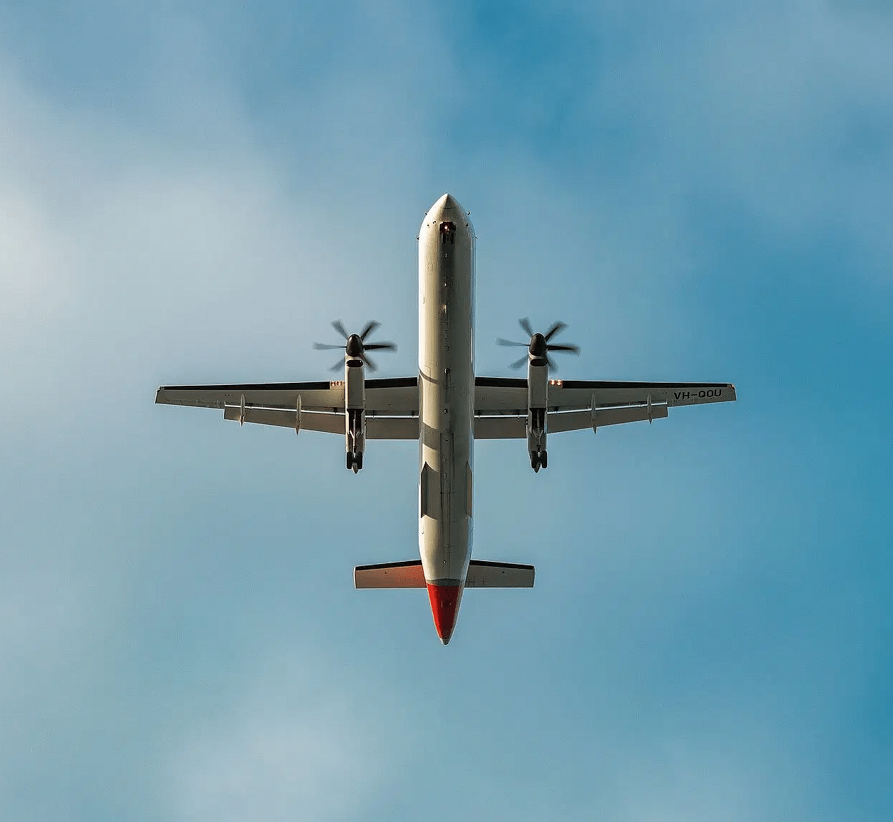 An aeroplane flying high in the sky with a bright blue sky in the background.