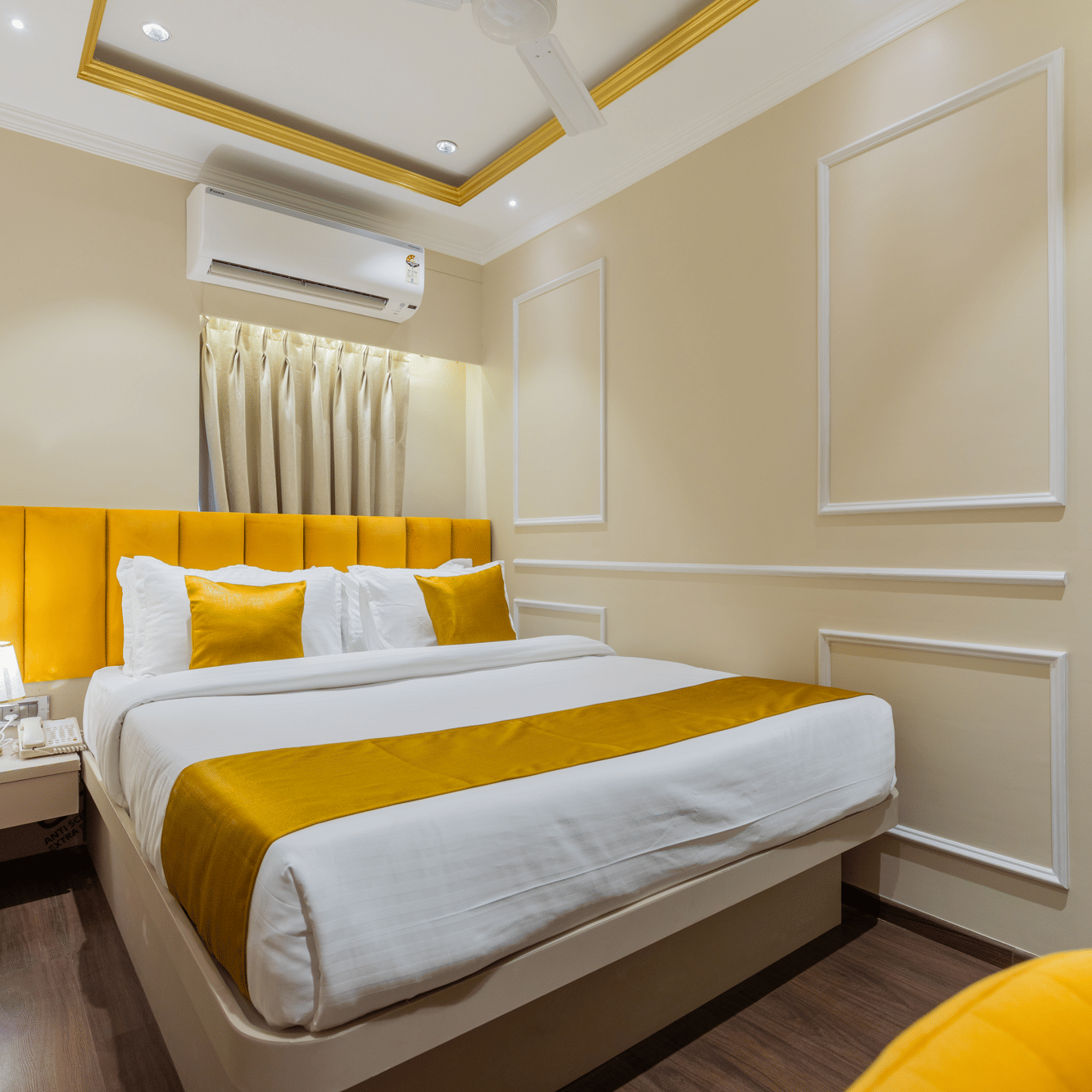 A comfortable double bed with a bright yellow headboard, white linens, and warm ambient lighting - Home2 Residency, Mumbai Airport