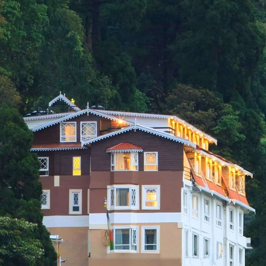 Front facade view of Summit Hermon Hotel & Spa, Darjeeling, surrounded by lush greenery