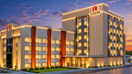 Illuminated multi-story facade and architectural exterior of Lords Inn Somnath during a vibrant sunset.